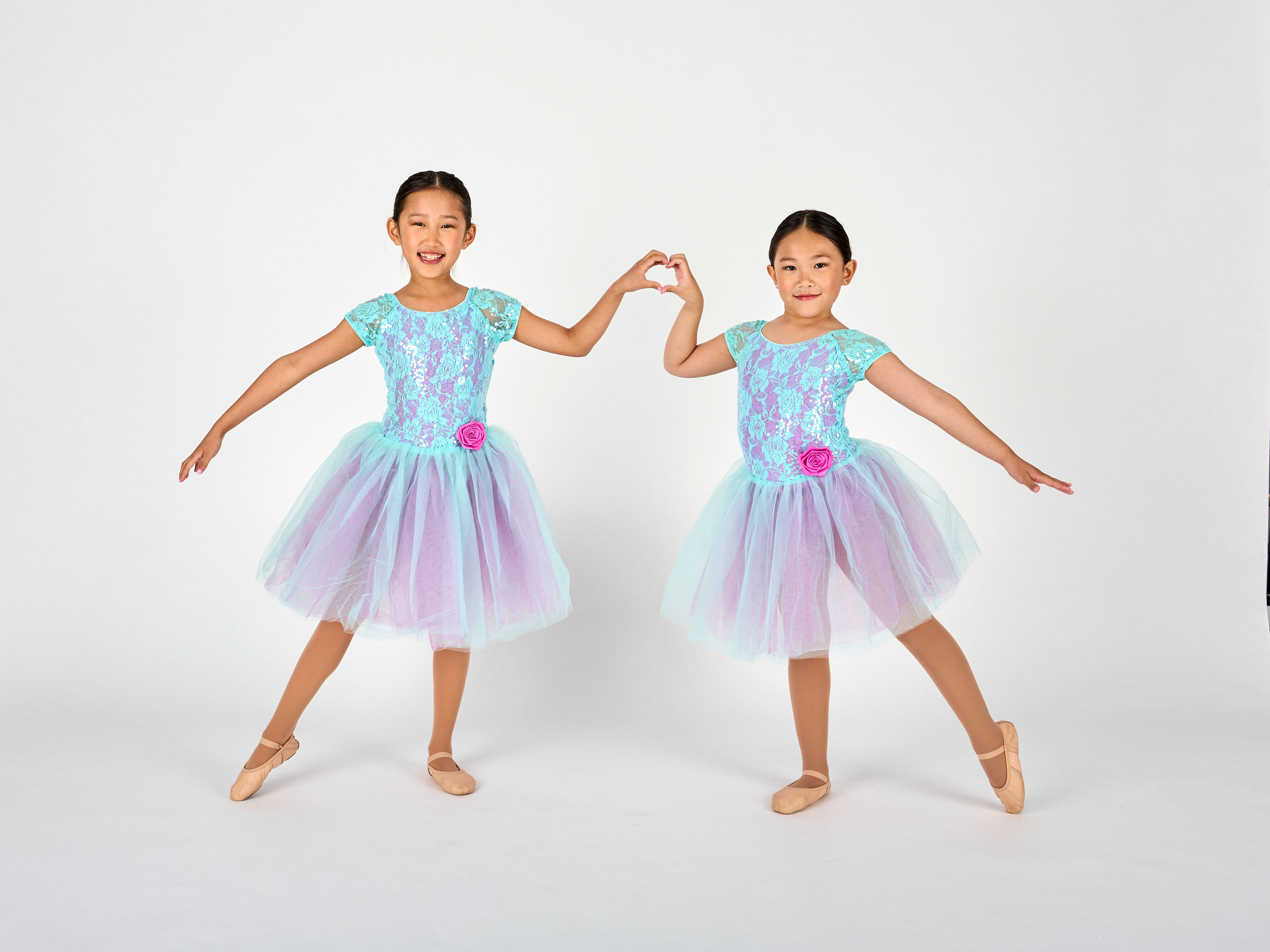 Two young Dance Connections dancers in matching tutus making a heart together