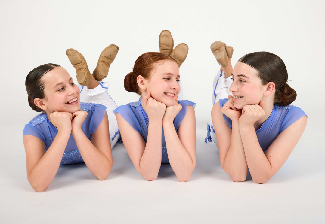 Three Dance Connections dancers in blue costumes smiling together